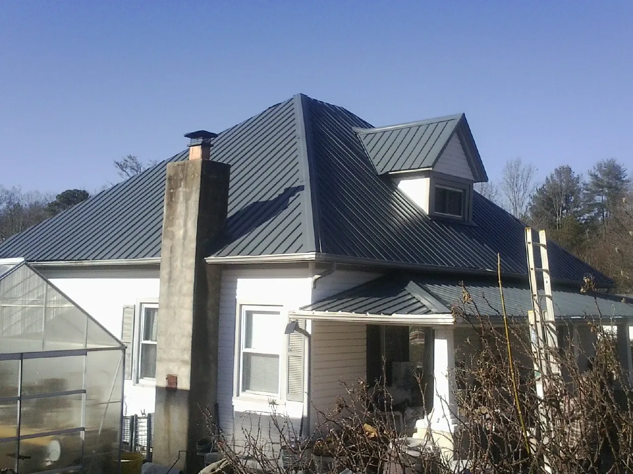 Dark blue standing seam metal roof on a white farmhouse with dormer — Slate & Tile Roof Repair by Roofing Brothers in Newcomerstown