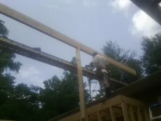 Carpenter setting a ridge beam over a new addition frame — Ice Dam Removal by Roofing Brothers in Newcomerstown