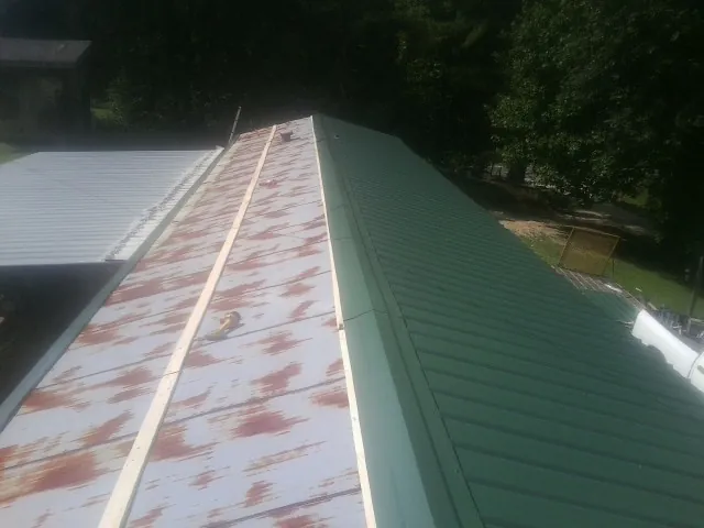 Old rusted panels beside newly installed green metal roofing — Wind Damage Roof Repair by Roofing Brothers in Newcomerstown