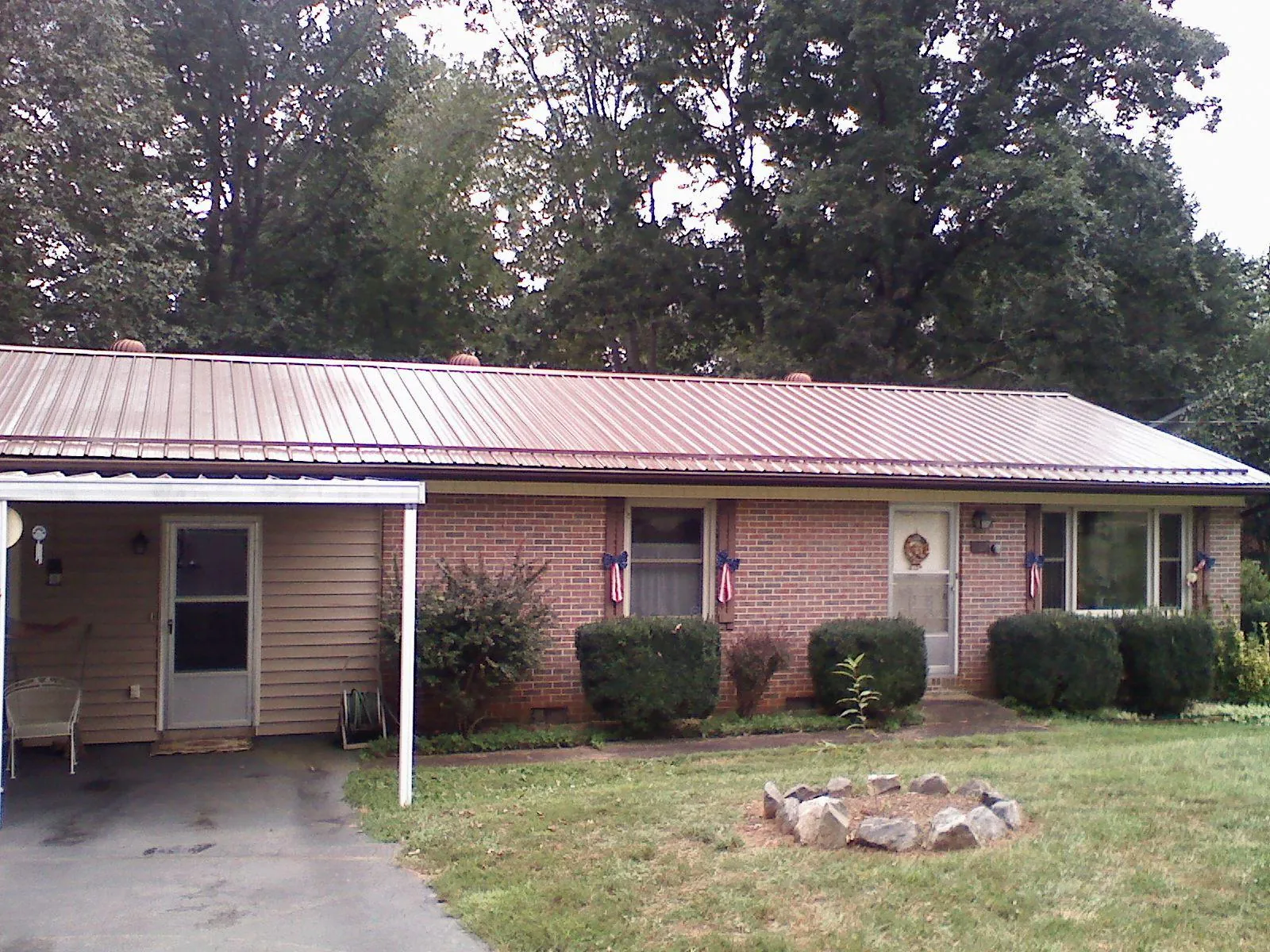 Bronze metal roof and carport on a brick ranch home — Roof Repair work by our crew in Newcomerstown