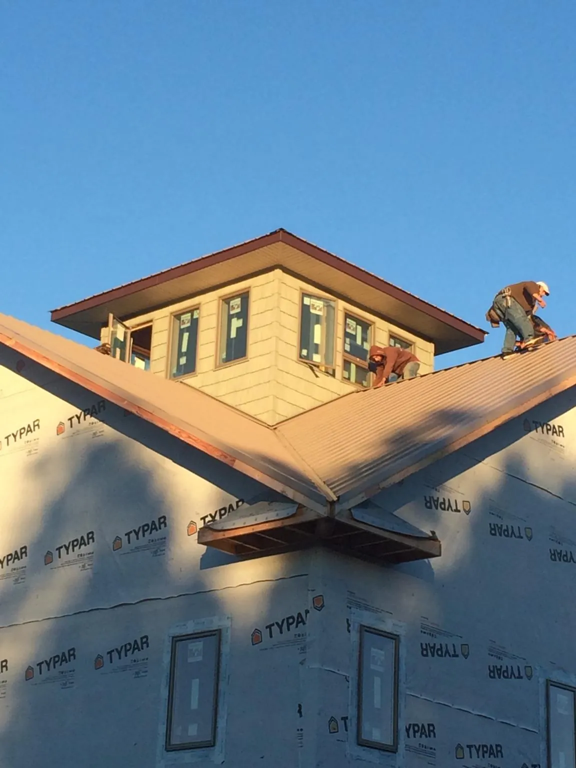 Roofers working around a rooftop cupola on a new metal roof at sunset — Roof Waterproofing in Newcomerstown by Roofing Brothers